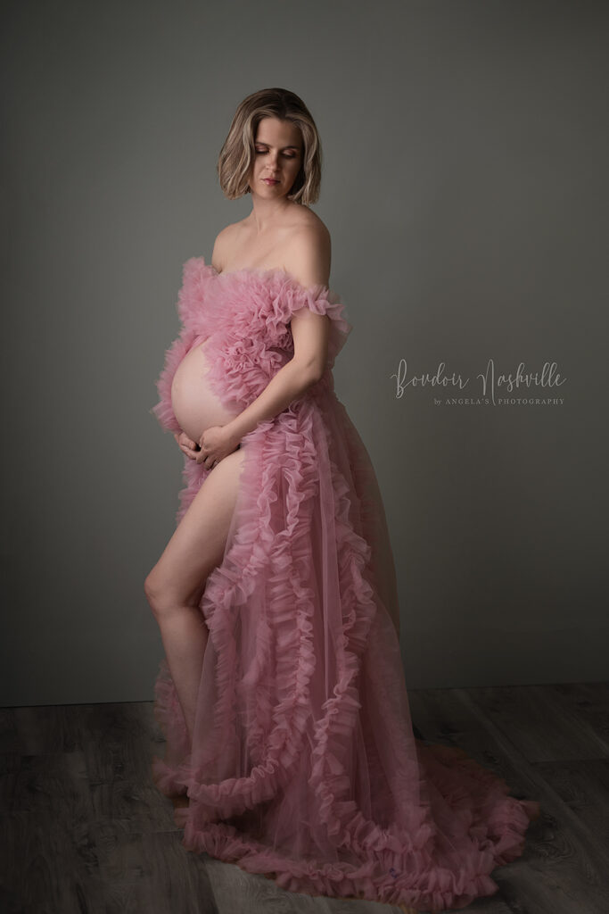 Maternity boudoir photo in a lovely fluffy pink glamorous gown.